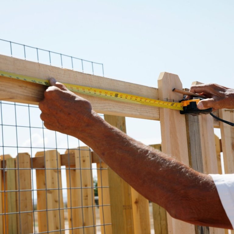 Fence contractor measuring a gate frame during installation