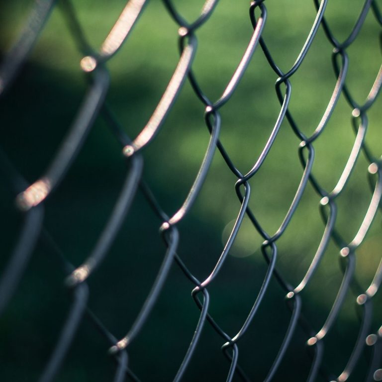Dark coated chain link mesh against a green backyard in Montgomery County