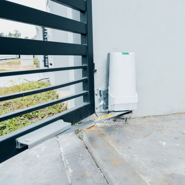 Automatic gate opener and control box mounted beside a driveway gate