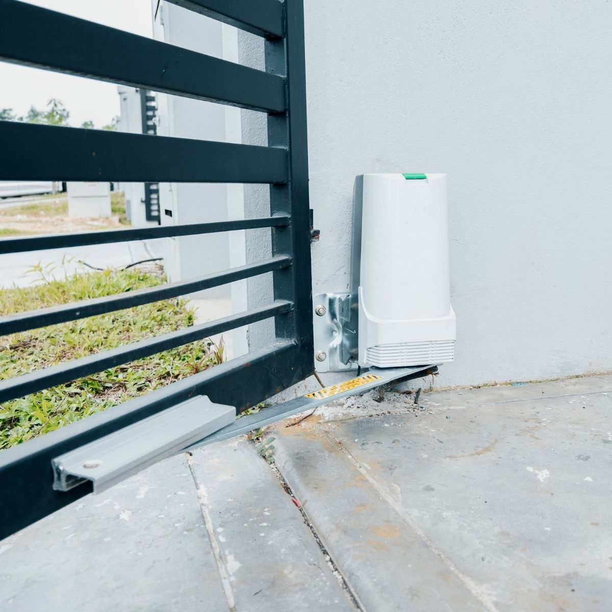 Automatic gate opener and control box mounted beside a driveway gate in Conroe Texas