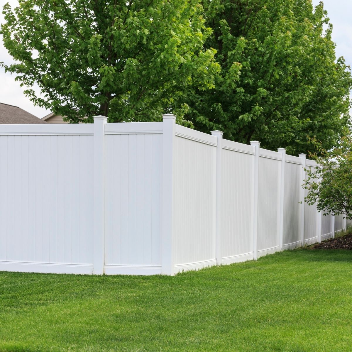 White vinyl privacy fence around a landscaped Conroe Texas backyard